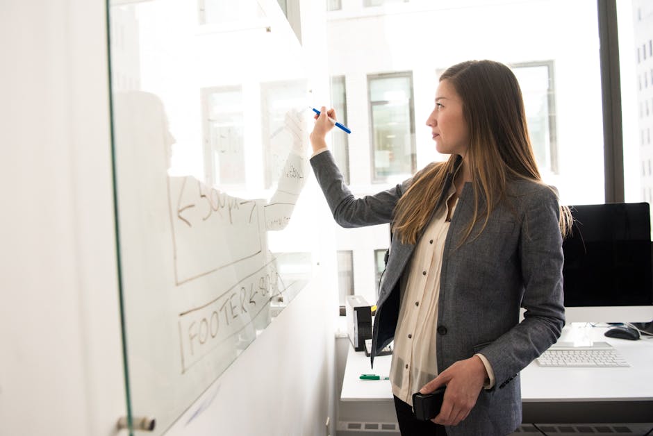pexels-photo-1181534-1181534 Woman Wearing Gray Blazer Writing on Dry-erase Board